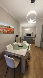 阿斯蒂Appartamento CA' GIARDINO的餐桌、白色椅子和绘画