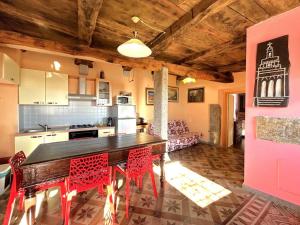 a kitchen with a table and red chairs in a room at LA CASA DEI SOGNI appartamento Glicine in Pisano