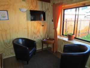 a room with two chairs and a tv and a window at CABAÑITA EN ARRIENDO Neltume huilo huilo Chile in Neltume