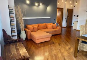 een woonkamer met een oranje bank en houten vloeren bij Villa Mattei Franciacorta in Villa Pedergnano