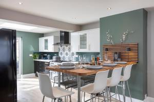 a kitchen with a wooden table and white chairs at Melrose- Beautiful 4 Bedroom Home With Parking in Brighton & Hove