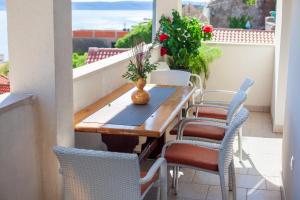 Una mesa y sillas de madera en un balcón. en Apartmani Panorama, en Igrane
