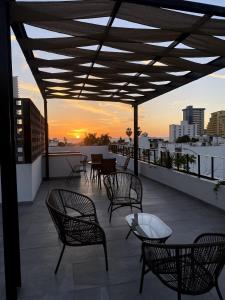 un patio en la azotea con sillas, mesas y una puesta de sol en few steps from the beach, at golden zone, en Mazatlán