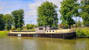 una barca con un edificio sul lato di un fiume di La Péniche - Gîte de groupe insolite a Saint-Omer