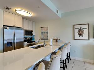 a kitchen with a sink and a counter with chairs at Cassine Station 305 - Sea Ya in Santa Rosa Beach