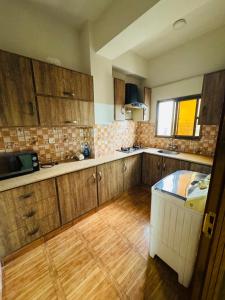 a kitchen with wooden cabinets and a table in it at 2 Bedrooms Deluxe Family Apartment Islamabad-HS Apartments in Islamabad