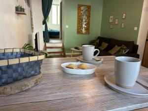 a wooden table with two cups and a bowl of food at Cœur d'émeraude in Moissac