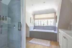 a bathroom with a bath tub and a window at Nest Stay By The Butler Collection in Pulborough +56 photos