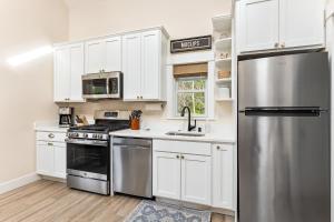Una cocina con gabinetes blancos y un refrigerador de acero inoxidable. en Wayfinder by Seabrook Hospitality, en Pacific Beach