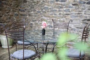 a glass table with chairs and a vase with flowers at Le Mosaïque, proche gare, terrasse, parking privé in Laval