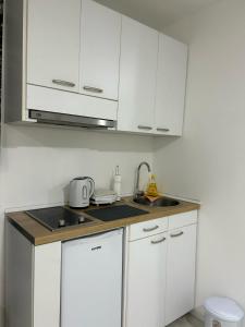 eine weiße Küche mit weißen Schränken und einer Spüle in der Unterkunft M-Home Mostar in Mostar + 1 Foto