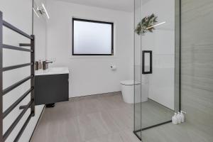 a bathroom with a toilet and a glass shower at Central Couples Retreat - Mangawhai Heads Unit in Mangawhai +9 photos