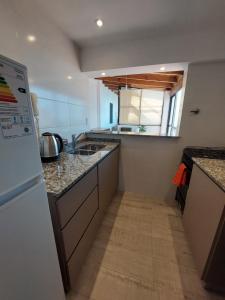 a kitchen with a white refrigerator and a sink at Sol de la Perla in Mar del Plata +2 photos