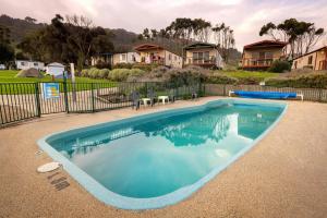 a large swimming pool in a yard with houses at Cozy Cabin by the beach in Apollo Bay