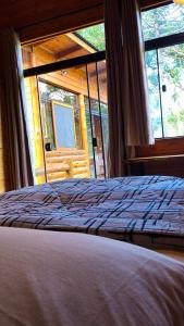 a bedroom with a bed and a large window at Cabana Fruta Fina - Urubici/SC in Grão Pará