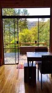 a room with a table and a view of a deck at Cabana Fruta Fina - Urubici/SC in Grão Pará