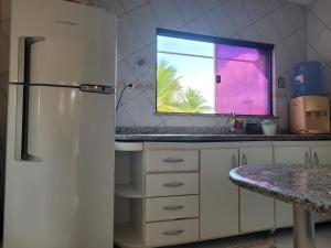 a kitchen with a refrigerator and a window at Cacha Pregos Vera Cruz - BA in Vera Cruz de Itaparica