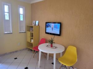a room with a table and chairs and a tv on a wall at Cacha Pregos Vera Cruz - BA in Vera Cruz de Itaparica