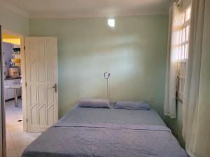 a bedroom with a bed and a window and a door at Cacha Pregos Vera Cruz - BA in Vera Cruz de Itaparica +10 photos