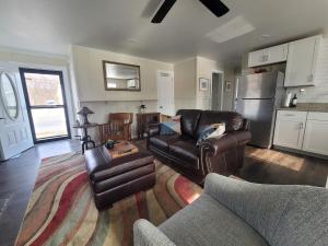 a living room with leather furniture and a kitchen at Riverfront Cottage in Owego in Owego
