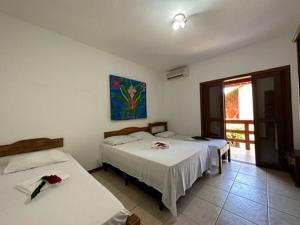 a room with two beds and a window at Pousada Sunset in Itacaré
