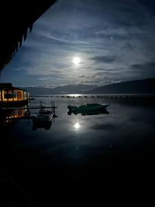 a boat on the water at night with a full moon at The Mussel House in Ksamil