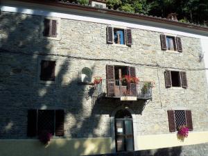 a stone building with a balcony with flowers on it at B&B Le Limentre in San Pellegrino al Cassero
