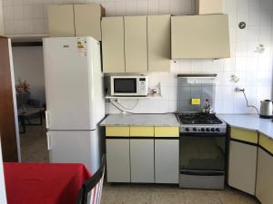 a kitchen with white cabinets and a white refrigerator at Edelweiss, amplio departamento in Comodoro Rivadavia