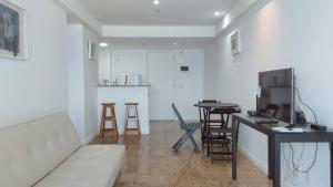 Una sala de estar con un sofá y una mesa y una cocina. en Flat Residencial Praia da Barra, Piscina e Sauna - Frente Mar D68508, en Río de Janeiro