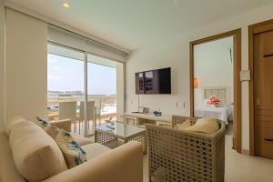 a living room with white furniture and a large window at Mágico Oasis en Baia Kristal Vista a la Laguna 2BR in Cartagena de Indias