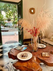 a wooden table with plates and a vase with dried grass at Mohana in Puerto Colombia