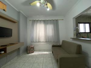 Una sala de estar con un sofá y un televisor. en Apto 2min da praia Ocian! Perto da Estatua Netuno!, en Samaritá