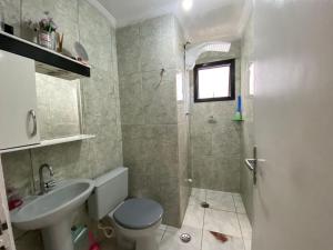 Un baño con lavabo, inodoro y ducha. en Apto 2min da praia Ocian! Perto da Estatua Netuno!, en Samaritá