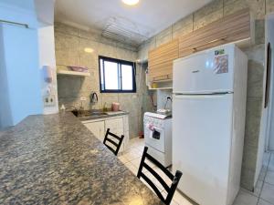 cocina con nevera blanca y encimera en Apto 2min da praia Ocian! Perto da Estatua Netuno!, en Samaritá 5 fotos más