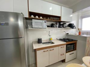 a kitchen with a stainless steel refrigerator and a sink at Kitão Frente Mar Na Tupi! in Samaritá