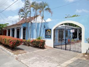 a blue building with a gate and palm trees at Hotel El Patio in Tlacotalpan