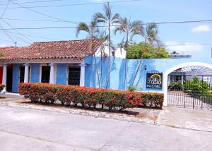 a blue building with red flowers in front of it at Hotel El Patio in Tlacotalpan