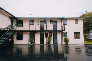 a white house with a balcony and a parking lot at 301 Bealey Ave Motel Very Close to City Centre and Hagley park in Christchurch