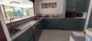 a kitchen with blue cabinets and a sink and a window at La Villa de la plage à Poé in Bourail