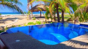 a large blue swimming pool next to a beach at Bungalows Tree Tops - Adults Only in Zihuatanejo