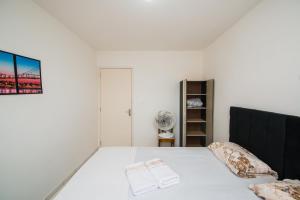 1 dormitorio con cama blanca y cabecero negro en Apartamento próximo a BR 101 ideal para viajantes, en Palhoça
