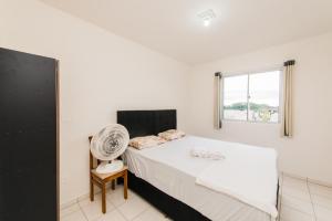 Un dormitorio con una cama con ventilador y una ventana. en Apartamento próximo a BR 101 ideal para viajantes, en Palhoça