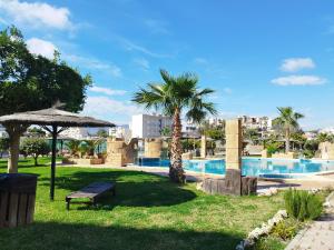 a park with a bench and a palm tree next to a pool at Ático Dos Bahías in Águilas