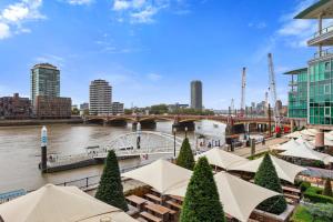 a view of a river with tables and umbrellas at River View London Eye Vauxhall 2 Bedroom Apartment in London