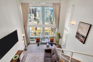 a living room with a couch and a large window at Two-Story Loft with a High-rises view and Rooftop Deck in Vancouver
