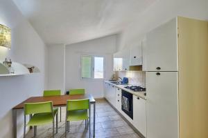 a kitchen with a wooden table and green chairs at Djadsal Moradias - by Bobbywashere in Santa Maria