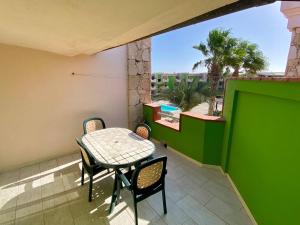 a table and chairs on a balcony with a green wall at Djadsal Moradias - by Bobbywashere in Santa Maria