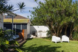 two white chairs in a yard next to a house at Ro-ana for 8, Gerringong in Gerringong