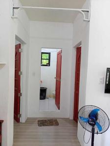Zimmer mit einem Flur mit roten Türen und einem Ventilator in der Unterkunft Vincent and Rose Home stay in Maricaban