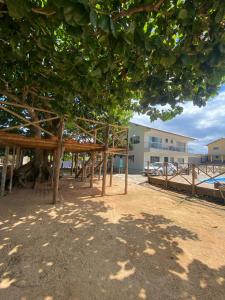 un padiglione di legno sulla spiaggia sotto un albero di Casa pé na areia - Brandão House a Saco dos Cações